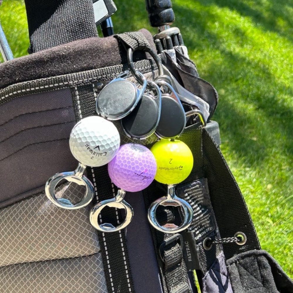 Golf ball bottle opener with retractable cord and carabiner.